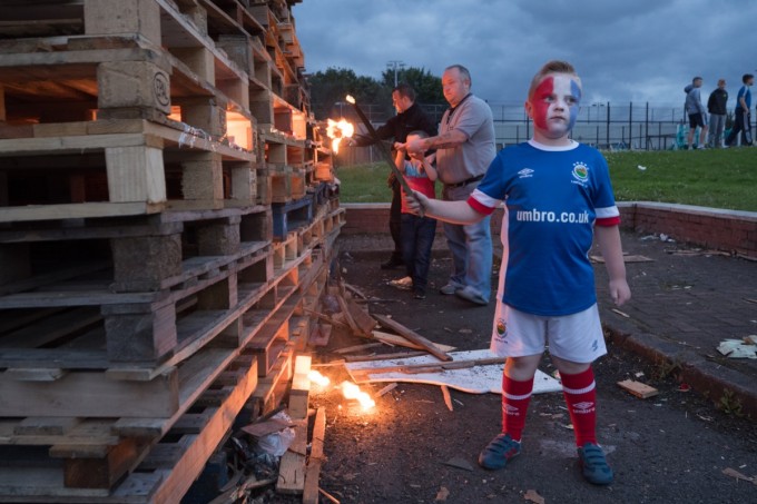 A boy poses for a picture before helping ignite a bonfire.