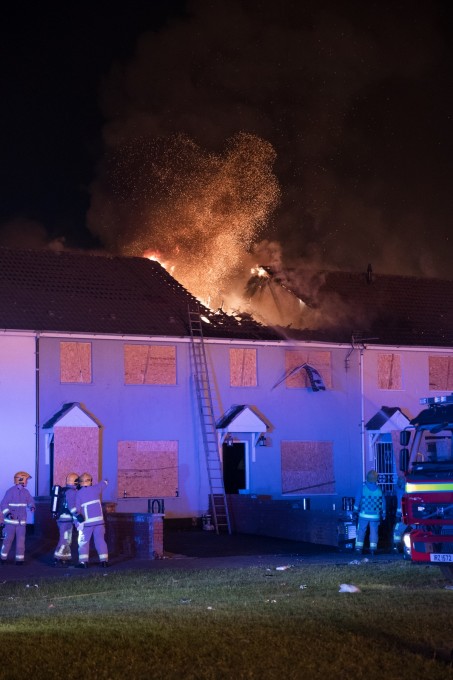 Despite boarding up windows and doors to protect houses from the Shankill bonfire’s spectacular embers, the roof of a nearby row house ignited, destroying multiple units. This is the moment the first roof collapsed.